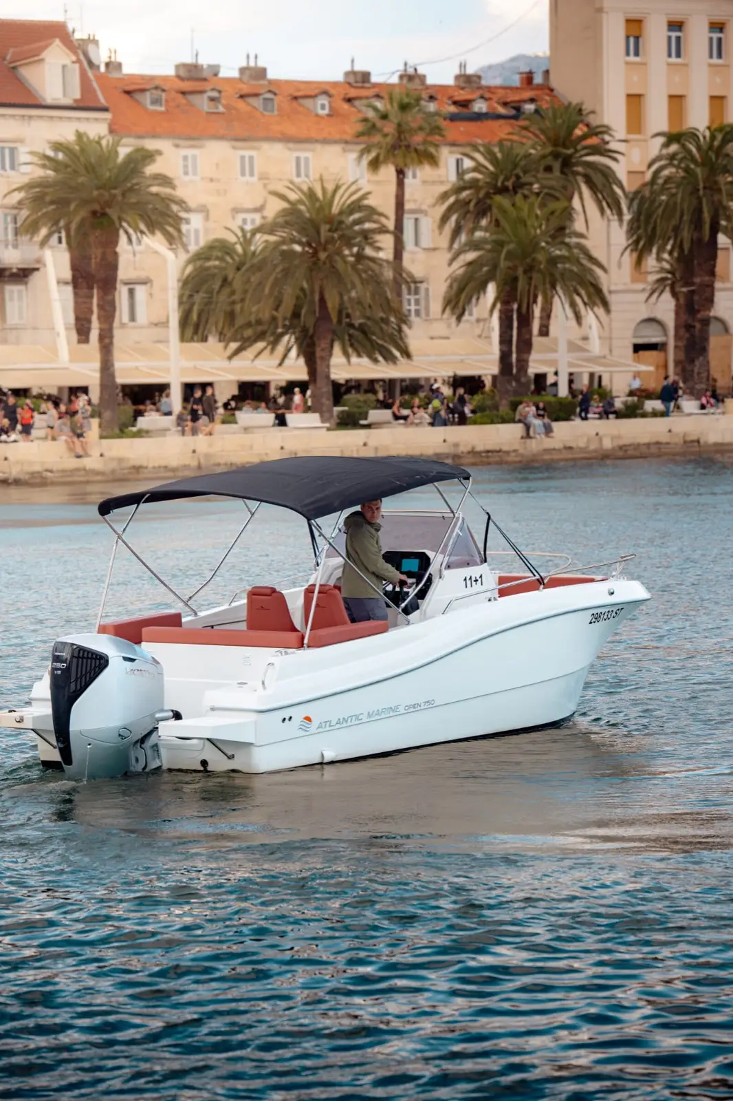 man on a boat feat buildings and palm trees behind him