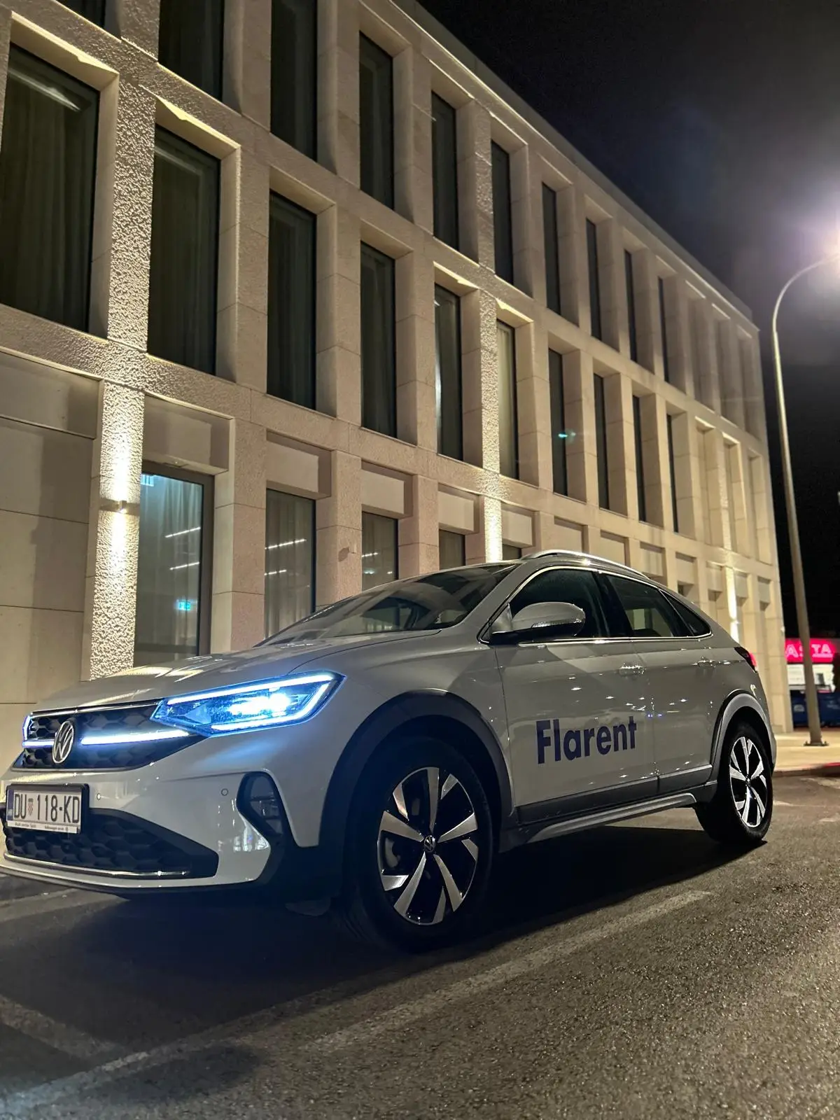 white car in front of a building by night