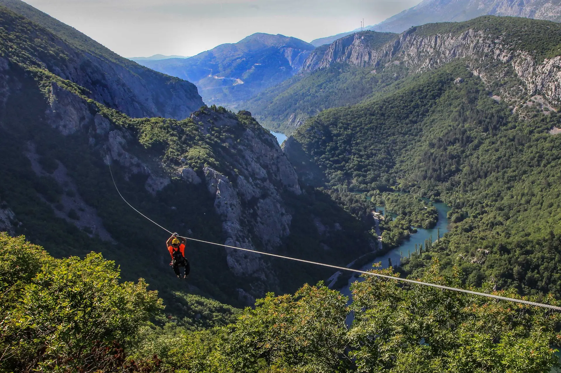 a person zip lines above river canyon